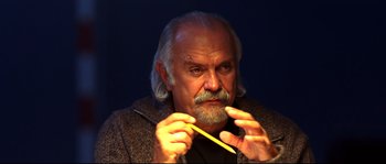 Movie still from “12” (2007), directed by Nikita Mikhalkov – An older man holding a yellow pencil in his hand; Close Up shot, Low angle