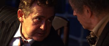 Movie still from “12” (2007), directed by Nikita Mikhalkov – A man in a suit is talking to another man in a suit; Close Up shot, Over the shoulder angle