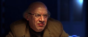 Movie still from “12” (2007), directed by Nikita Mikhalkov – An older man wearing glasses and a brown jacket; Close Up shot, Low angle