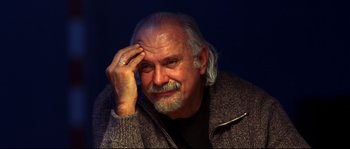 An older man with a beard and a ring on his finger