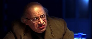 Movie still from “12” (2007), directed by Nikita Mikhalkov – An older man wearing glasses and a brown jacket; Close Up shot, High angle