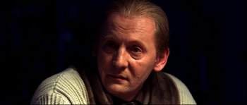 Movie still from “12” (2007), directed by Nikita Mikhalkov – An older man wearing a sweater and a tie; Close Up shot, Over the shoulder angle