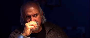 Movie still from “12” (2007), directed by Nikita Mikhalkov – An older man with long gray hair is holding his hand to his mouth; Close Up shot, Low angle