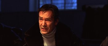 Movie still from “12” (2007), directed by Nikita Mikhalkov – A person sitting in a room; Close Up shot, Low angle