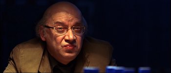 Movie still from “12” (2007), directed by Nikita Mikhalkov – An older bald man wearing glasses and a suit; Close Up shot, Over the shoulder angle