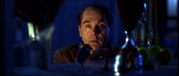 Movie still from “12” (2007), directed by Nikita Mikhalkov – A person sitting at a table; Close Up shot, Low angle