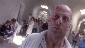 Movie still from “12 Monkeys” (1995), directed by Terry Gilliam – A man with a shaved head and a white towel around his neck; Close Up shot, Low angle