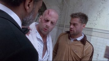 Movie still from “12 Monkeys” (1995), directed by Terry Gilliam – A man with a shaved head and two other men with a shaved head; Medium shot, Low angle