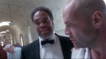 Movie still from “12 Monkeys” (1995), directed by Terry Gilliam – A man in a suit and a bow tie standing next to another man in a suit and a bow tie; Close Up shot, Low angle