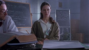 Movie still from “12 Monkeys” (1995), directed by Terry Gilliam – A woman sitting at a desk in front of a blackboard; Medium shot, Over the shoulder angle