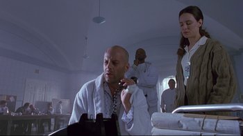Movie still from “12 Monkeys” (1995), directed by Terry Gilliam – A bald man in a white robe brushing his teeth; Medium shot, Low angle