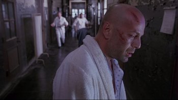 Movie still from “12 Monkeys” (1995), directed by Terry Gilliam – A man in a white bathrobe with a scar on his face; Medium shot, Low angle