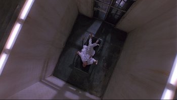 Movie still from “12 Monkeys” (1995), directed by Terry Gilliam – A man in white shirt and pants laying on the ground; Wide shot, Overhead angle