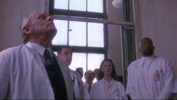 Movie still from “12 Monkeys” (1995), directed by Terry Gilliam – A group of people in lab coats standing in front of a window; Medium shot, Low angle