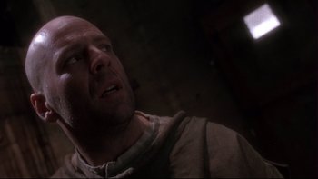 Movie still from “12 Monkeys” (1995), directed by Terry Gilliam – A bald man in a brown jacket looking up; Close Up shot, Low angle