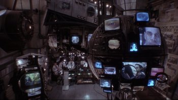 Movie still from “12 Monkeys” (1995), directed by Terry Gilliam – A room filled with lots and lots of televisions; Wide shot, High angle