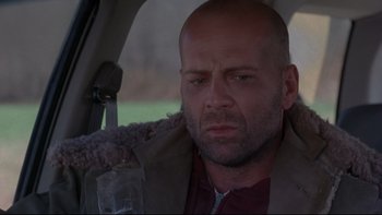 Movie still from “12 Monkeys” (1995), directed by Terry Gilliam – A man sitting in the back seat of a car; Close Up shot, Low angle