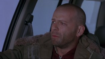 Movie still from “12 Monkeys” (1995), directed by Terry Gilliam – A bald man sitting in the back seat of a car; Close Up shot, High angle