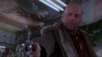 Movie still from “12 Monkeys” (1995), directed by Terry Gilliam – A man holding a gun while wearing a jacket; Close Up shot, Low angle
