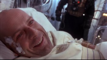 Movie still from “12 Monkeys” (1995), directed by Terry Gilliam – A man smiling for the camera while lying in bed; Close Up shot, High angle
