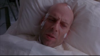 Movie still from “12 Monkeys” (1995), directed by Terry Gilliam – A bald man with bandages on his head is laying in a bed; Close Up shot, High angle