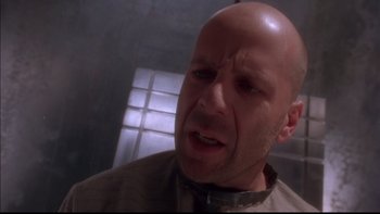 Movie still from “12 Monkeys” (1995), directed by Terry Gilliam – A bald man with a goatee is looking at the camera; Close Up shot, Low angle