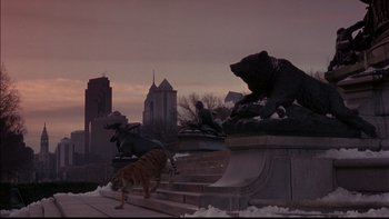 Movie still from “12 Monkeys” (1995), directed by Terry Gilliam – A statue of a bear and a tiger in the middle of a city; Extreme Wide shot, Low angle