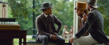 Movie still from “12 Years a Slave” (2013), directed by Steve McQueen – A man wearing a suit and a hat sitting on a bench; Medium shot, Over the shoulder angle
