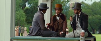 Movie still from “12 Years a Slave” (2013), directed by Steve McQueen – Two men in hats and suits sitting on a porch; Medium shot, Over the shoulder angle