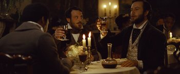 Movie still from “12 Years a Slave” (2013), directed by Steve McQueen – A man sitting at a table holding a glass of wine; Medium shot, Over the shoulder angle