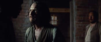 Movie still from “12 Years a Slave” (2013), directed by Steve McQueen – A man with long hair and a beard standing in front of a window; Close Up shot, Over the shoulder angle