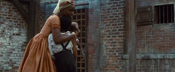 Movie still from “12 Years a Slave” (2013), directed by Steve McQueen – A woman carrying a baby in a sling; Medium shot, Low angle