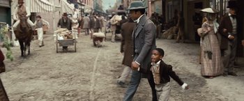 Movie still from “12 Years a Slave” (2013), directed by Steve McQueen – A man and a boy walking down a street; Wide shot, High angle
