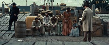Movie still from “12 Years a Slave” (2013), directed by Steve McQueen – A group of men and women sitting on a dock; Wide shot, High angle