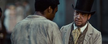 Movie still from “12 Years a Slave” (2013), directed by Steve McQueen – A man wearing a hat and a jacket talking to another man; Close Up shot, Over the shoulder angle
