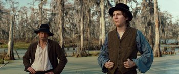 Movie still from “12 Years a Slave” (2013), directed by Steve McQueen – A man wearing a hat standing next to another man; Medium shot, Over the shoulder angle