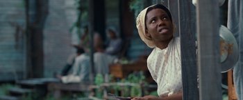 Movie still from “12 Years a Slave” (2013), directed by Steve McQueen – An african american woman wearing a head scarf and holding a knife in her hand; Close Up shot, Low angle