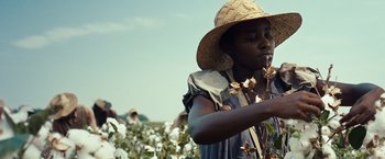 Movie still from “12 Years a Slave” (2013), directed by Steve McQueen – A woman in a straw hat standing in front of a field of cotton; Close Up shot, Low angle