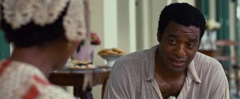 Movie still from “12 Years a Slave” (2013), directed by Steve McQueen – A man sitting in front of a table with food on top of it; Close Up shot, Over the shoulder angle