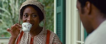 Movie still from “12 Years a Slave” (2013), directed by Steve McQueen – A woman wearing a hat and a red and white dress; Close Up shot, Low angle