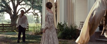 Movie still from “12 Years a Slave” (2013), directed by Steve McQueen – A woman standing in front of a building wearing a dress; Wide shot, Over the shoulder angle
