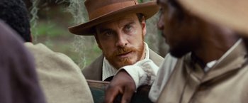 Movie still from “12 Years a Slave” (2013), directed by Steve McQueen – A person wearing a hat; Close Up shot, Over the shoulder angle