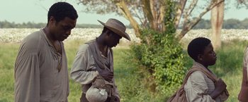 Movie still from “12 Years a Slave” (2013), directed by Steve McQueen – A man wearing a hat is holding a bag; Medium shot, Over the shoulder angle