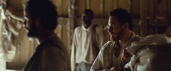 Movie still from “12 Years a Slave” (2013), directed by Steve McQueen – A man standing next to another man in a room; Medium shot, Over the shoulder angle