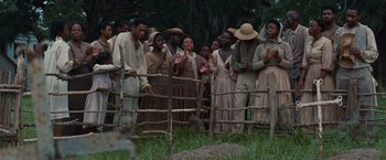 Movie still from “12 Years a Slave” (2013), directed by Steve McQueen – A group of people standing in a field near a wire fence; Wide shot, Over the shoulder angle