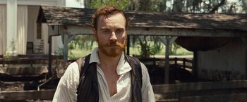 Movie still from “12 Years a Slave” (2013), directed by Steve McQueen – A man with a beard and a mustache is standing outside; Close Up shot, Over the shoulder angle