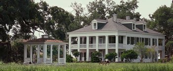 Movie still from “12 Years a Slave” (2013), directed by Steve McQueen – A large white two story house sitting in the middle of a green field; Extreme Wide shot, Low angle