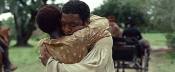 Movie still from “12 Years a Slave” (2013), directed by Steve McQueen – A man hugging another man in front of a crowd of onlookers; Close Up shot, Over the shoulder angle