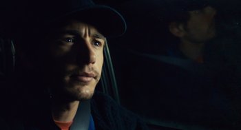 Movie still from “127 Hours” (2010), directed by Danny Boyle – A person in a car wearing a hat; Close Up shot, Over the shoulder angle