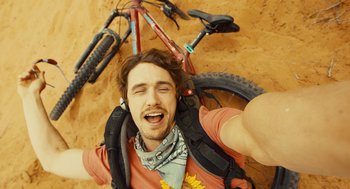 Movie still from “127 Hours” (2010), directed by Danny Boyle – A man taking a selfie with a bicycle in the background; Extreme Close Up shot, Overhead angle